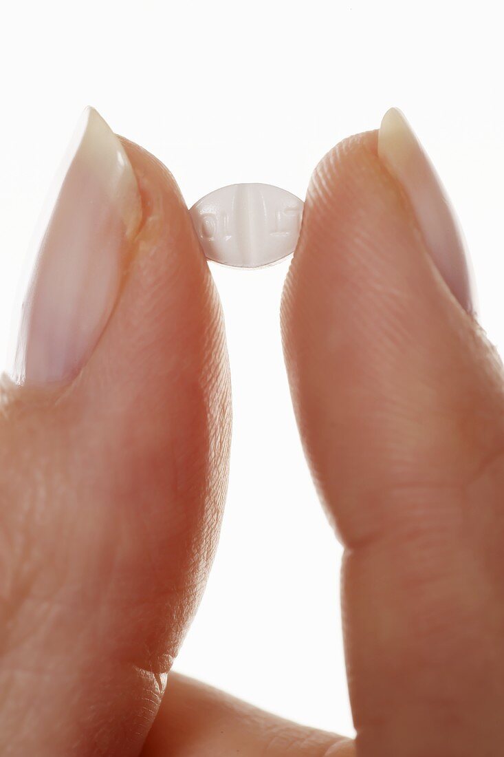 An allergy tablet between two fingers