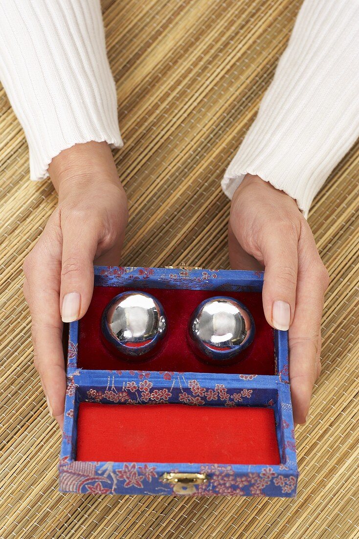 Hands holding a box of qi gong balls