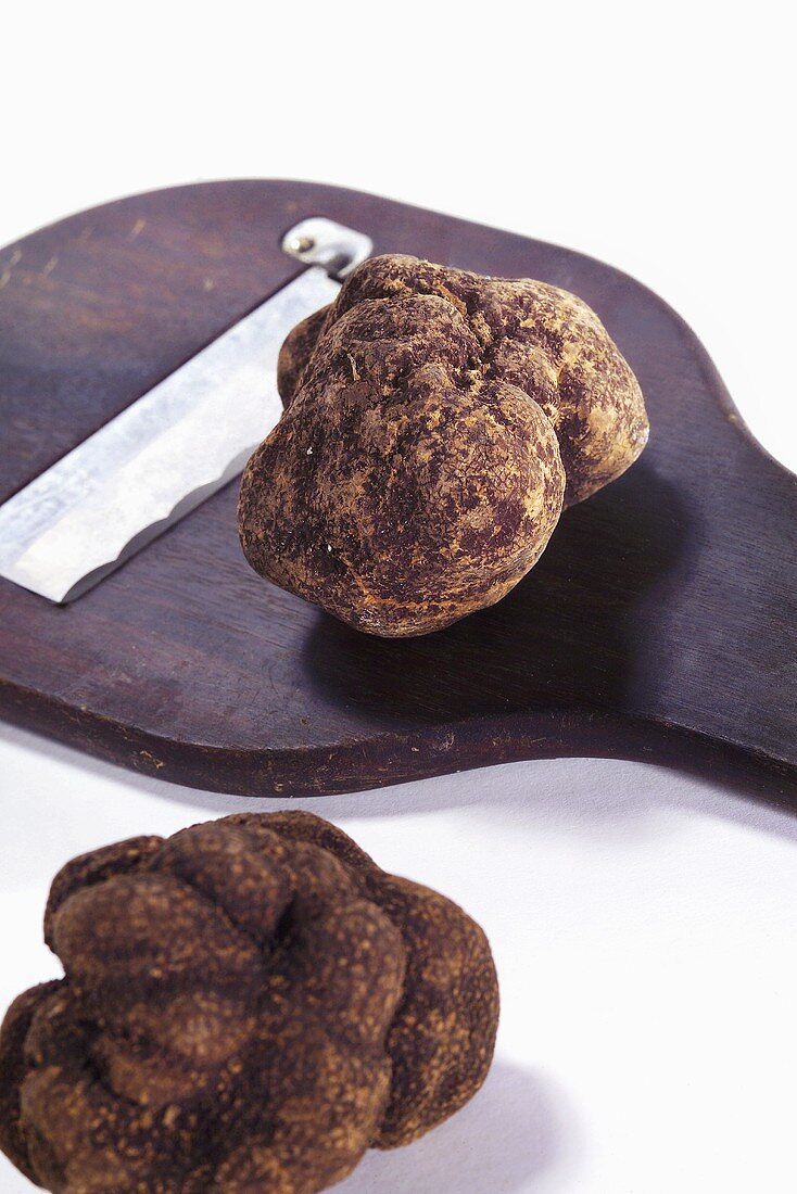 Two black truffles and a truffle slicer