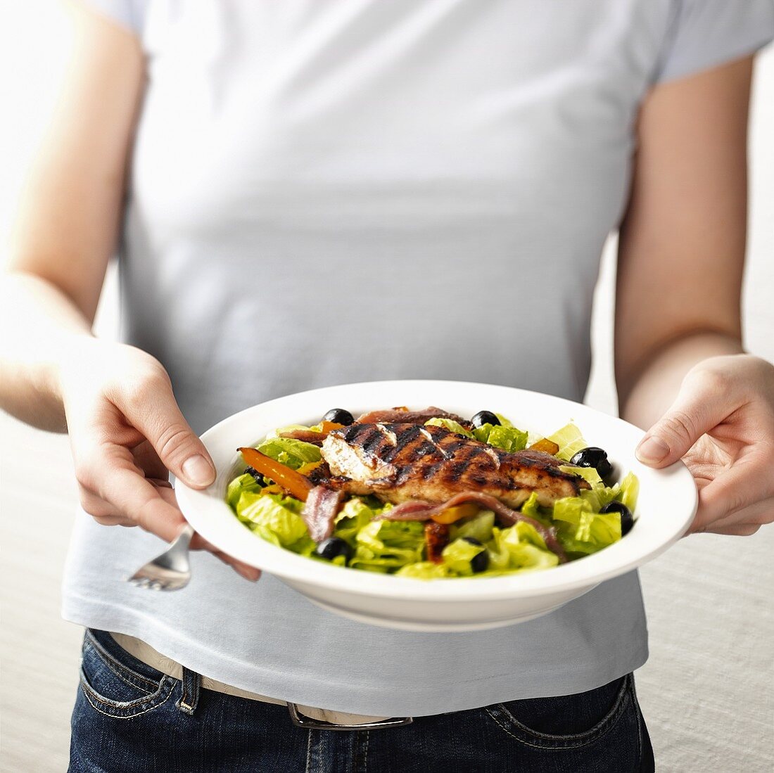 Frau hält einen Salat mit gegrilltem Hühnchenfilet