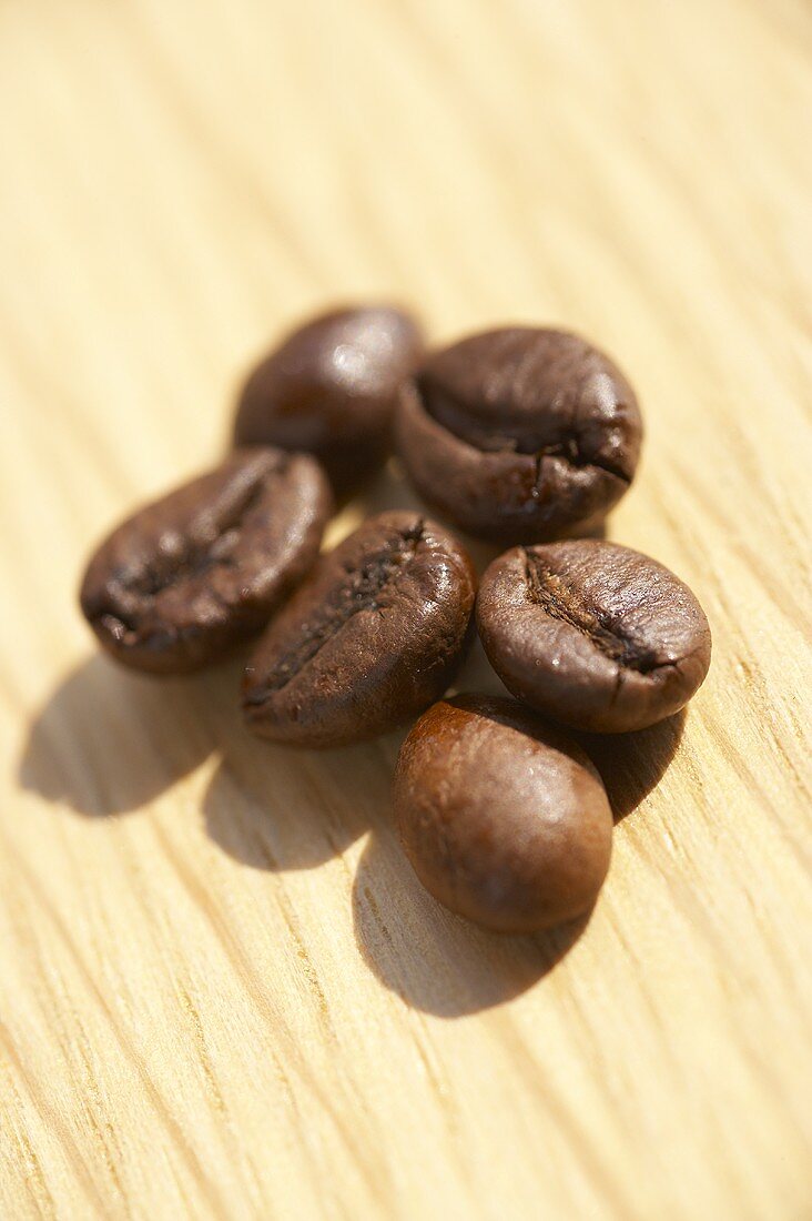 Six coffee beans on a wooden platter
