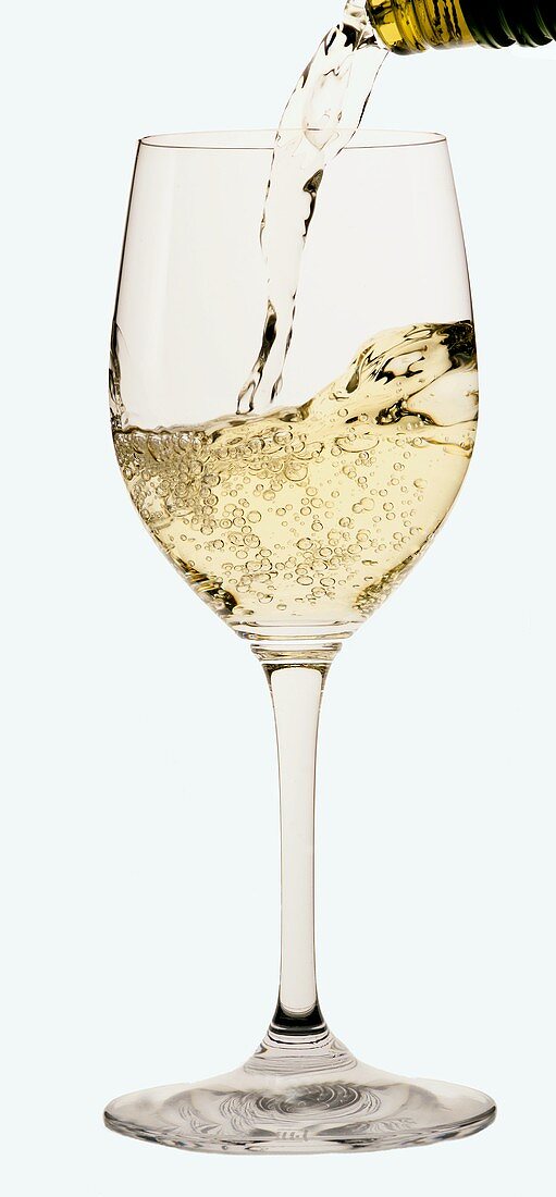 Weißwein wird in ein Weissweinglas gegossen