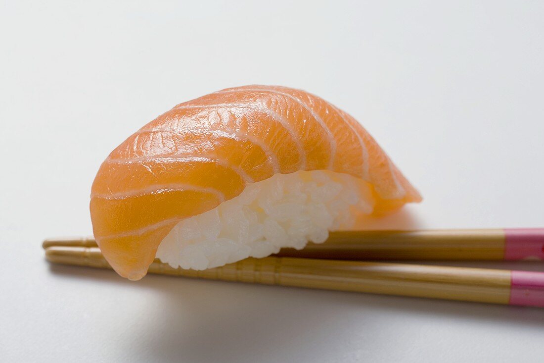 Nigiri sushi with salmon on chopsticks
