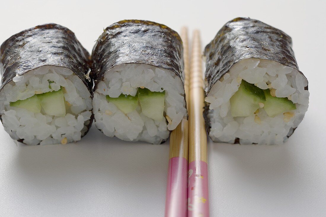 Drei Maki-Sushi mit Gurke und Essstäbchen