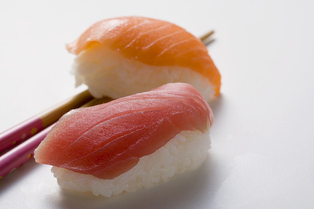 Nigiri-Sushi mit Thunfisch und Lachs, daneben Essstäbchen