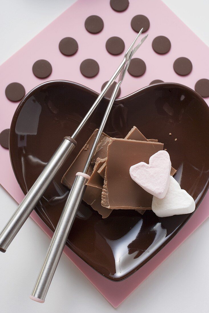 Small bowl with chocolate pieces, marshmallow & fondue forks