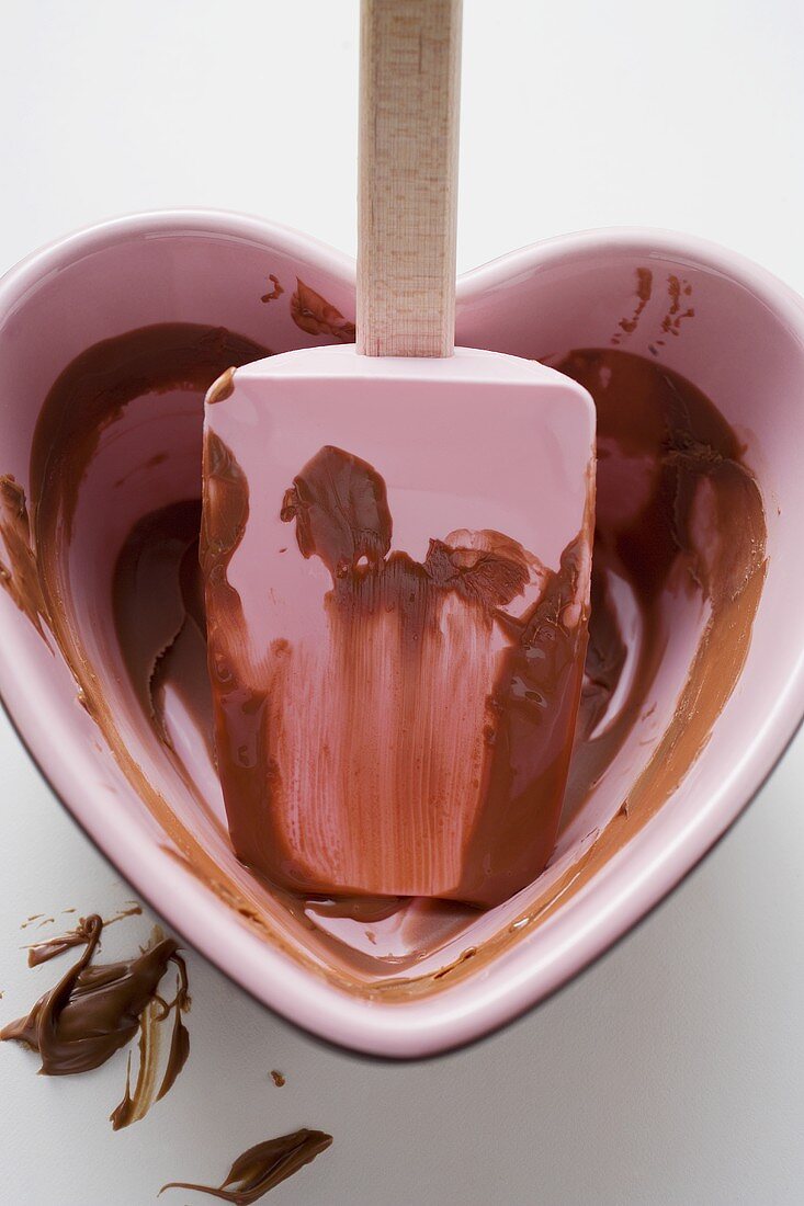 Heart-shaped bowl with mixing spoon & remains of chocolate sauce