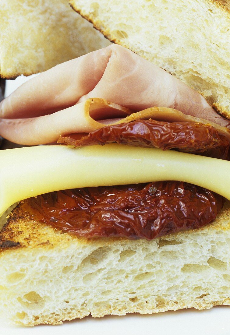 Sandwich mit Schinken, Käse und getrockneten Tomaten