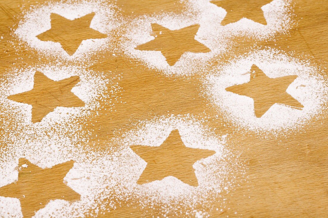 Star shapes outlined in icing sugar on wooden background