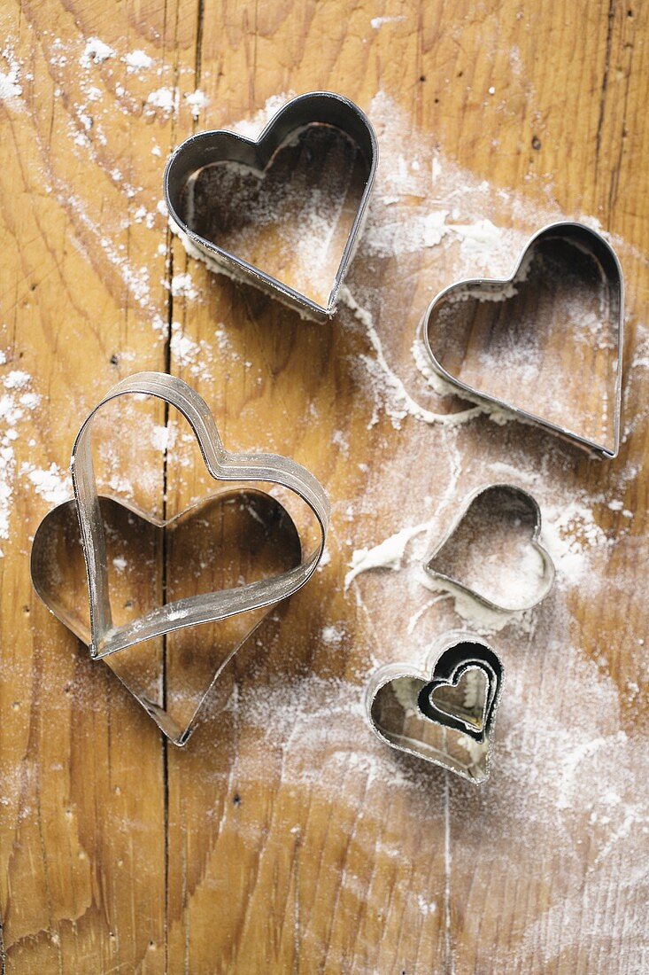 Heart-shaped biscuit cutters on floured board