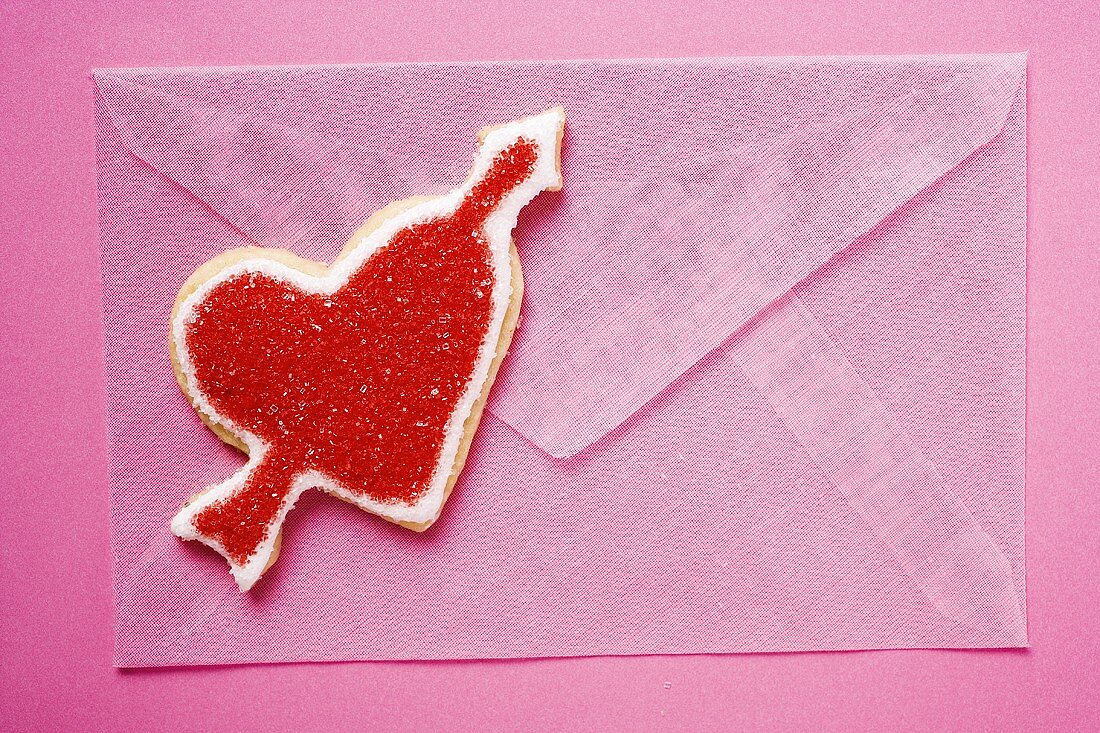 Pink envelope and red heart-shaped biscuit with arrow
