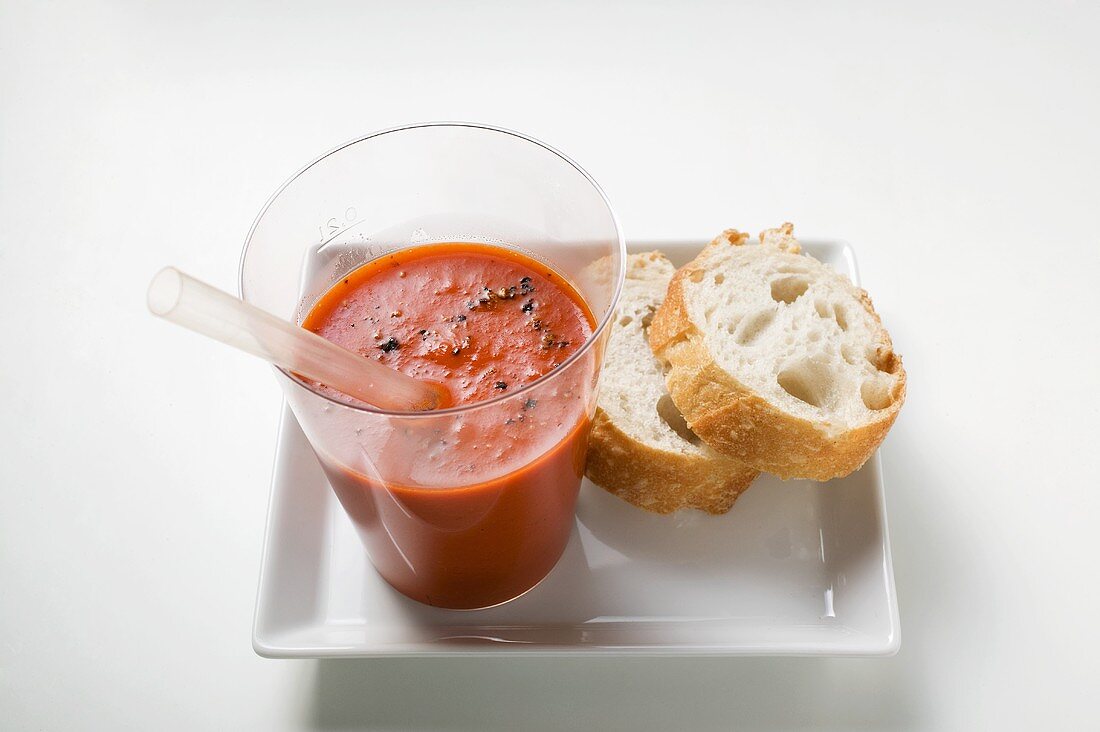 Ein Glas Paprika-Gemüse-Smoothie mit Trinkhalm und Weißbrot