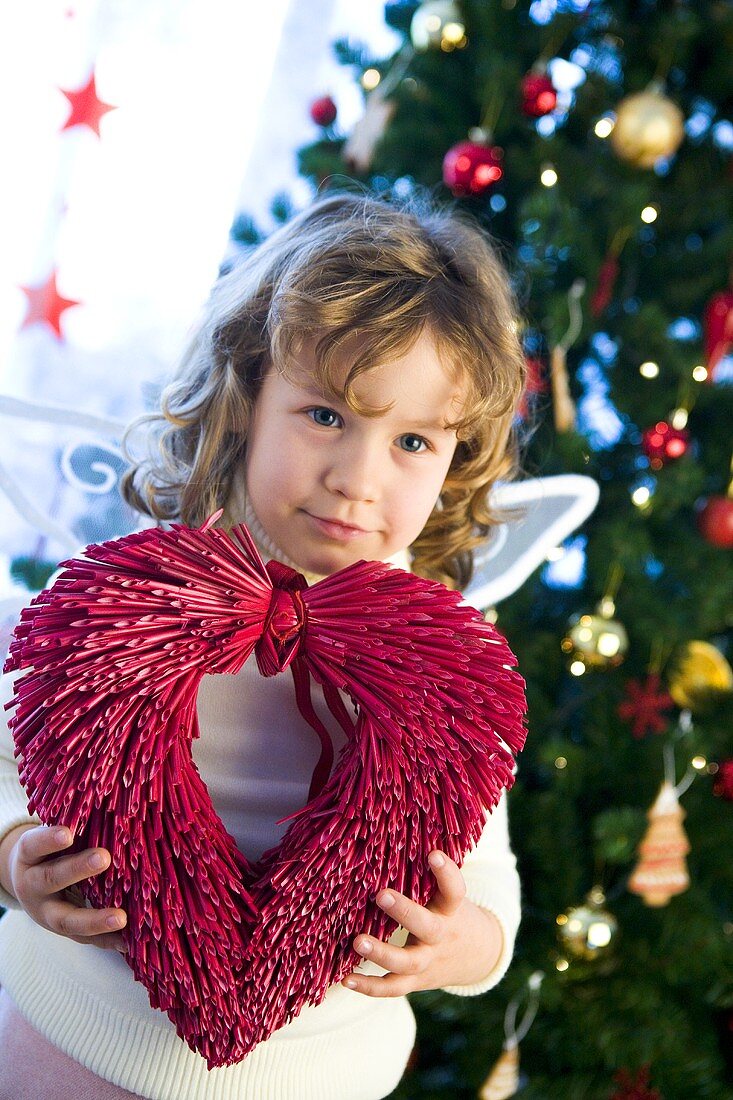 Girl dressed as angel in front of Christmas tree