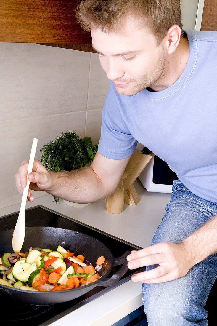 Young man stir-fying vegetables