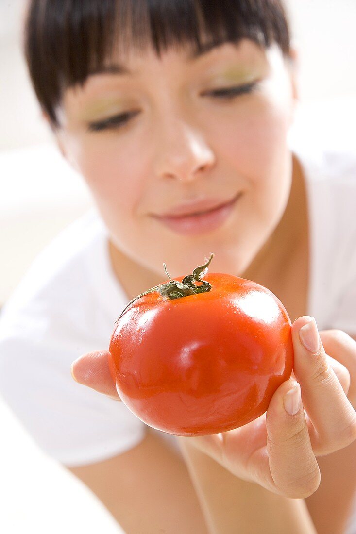 Junge Frau hält eine Tomate auf der Hand