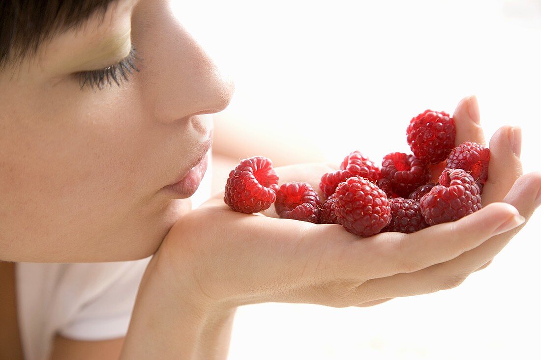 Young woman holding raspberries in her hand