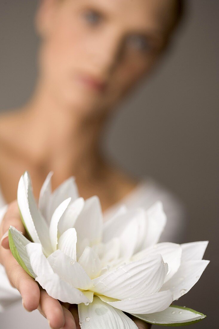 Junge Frau hält eine weiße Seerose in der Hand