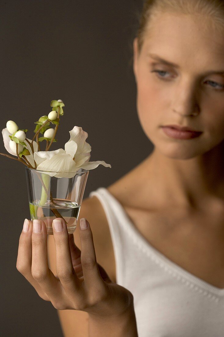 Young woman holding glass with white Christmas rose