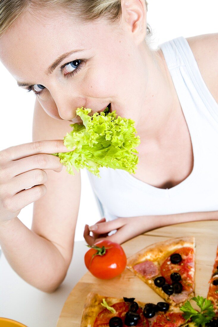 Young woman eating a lettuce leaf