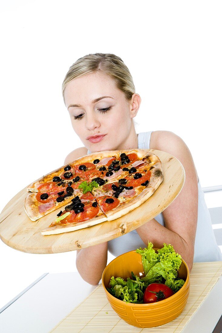Junge Frau hält Pizza auf Pizzabrett