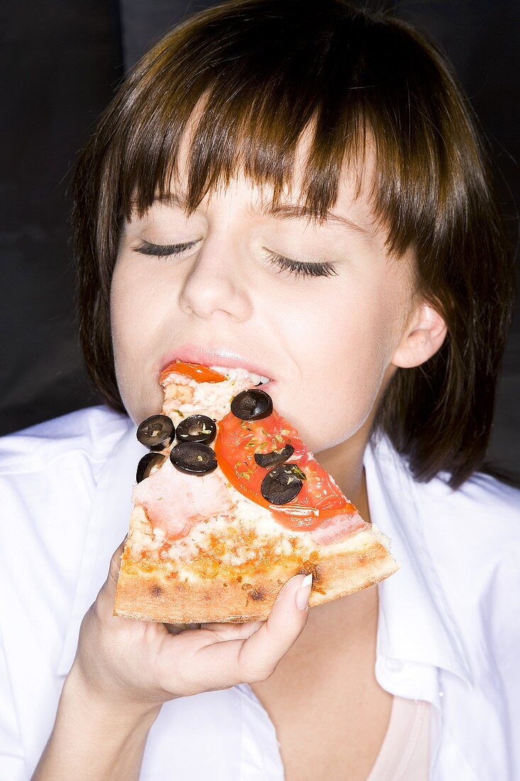 Young woman eating a slice of pizza