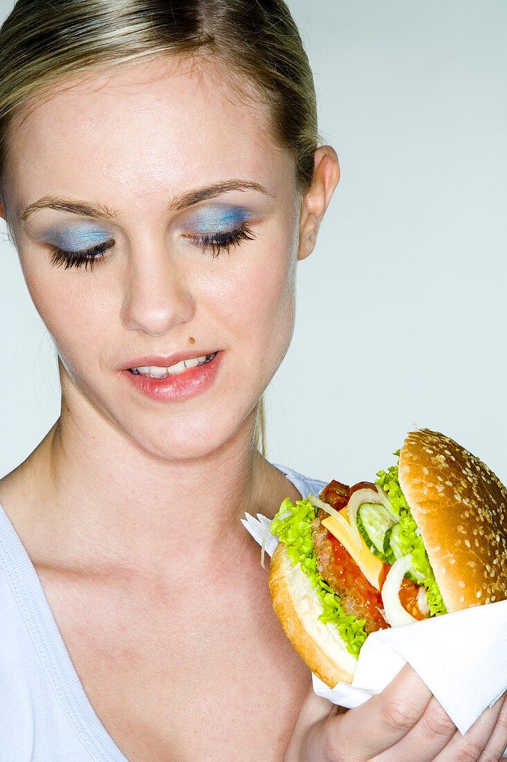 Junge Frau hält Hamburger in der Hand