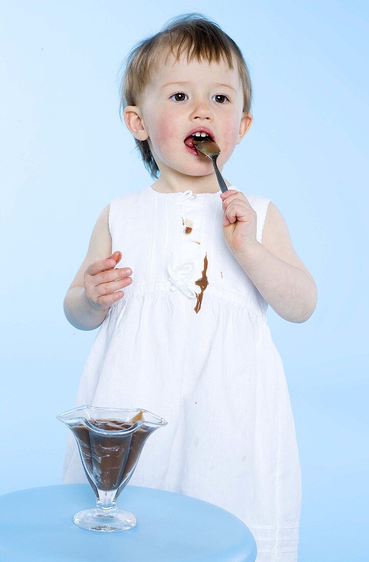 Small girl eating chocolate pudding