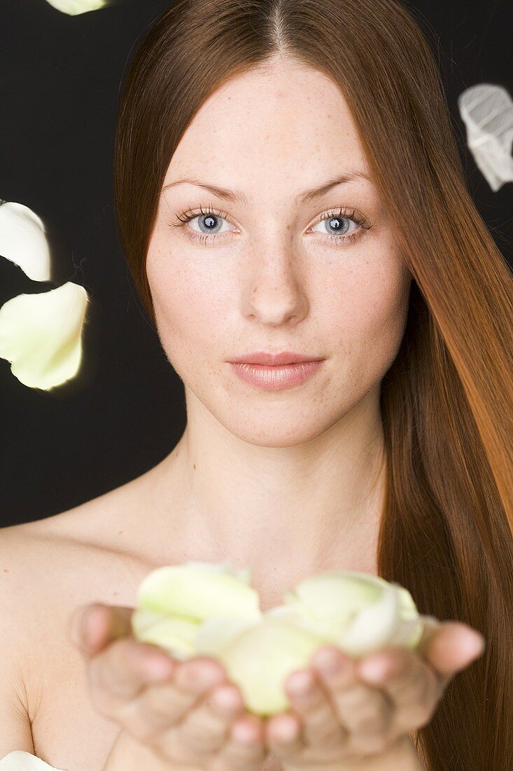 Red-haired woman with white rose petals