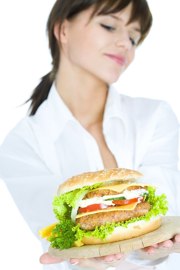 Young woman holding a giant hamburger on a board