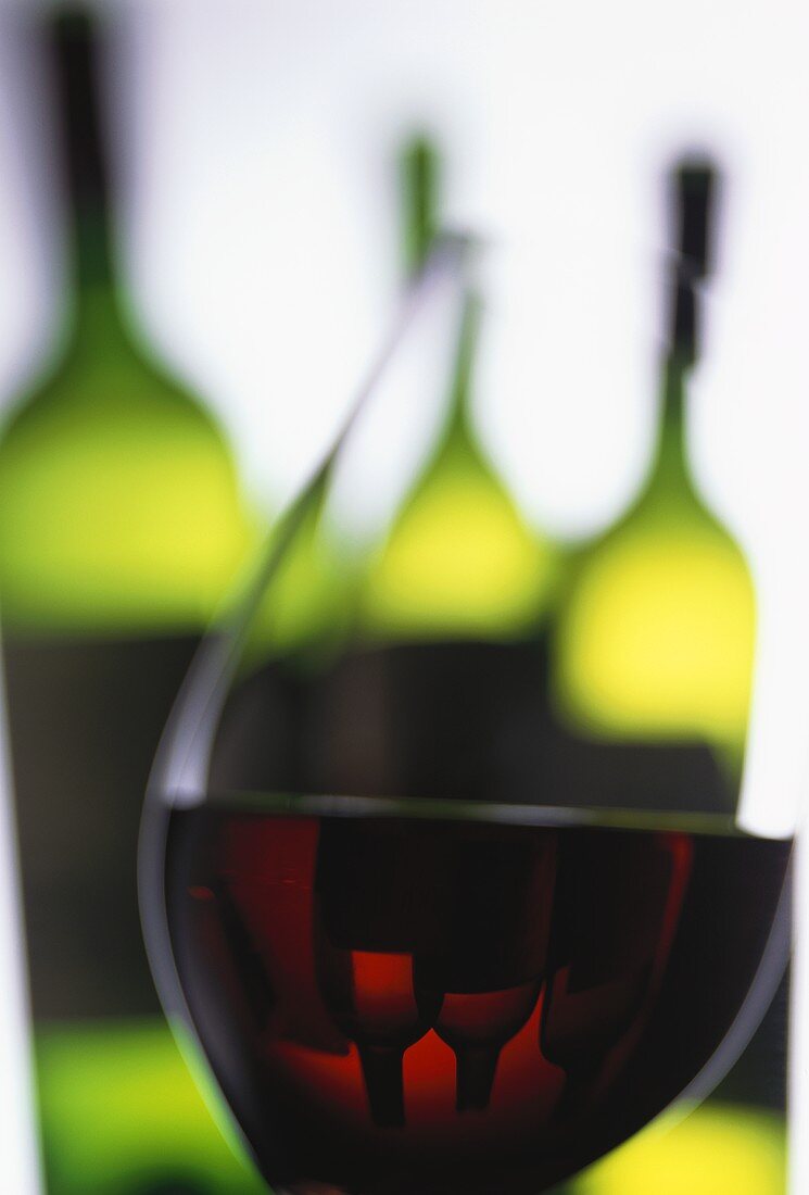 Rotweinglas vor Weinflaschen