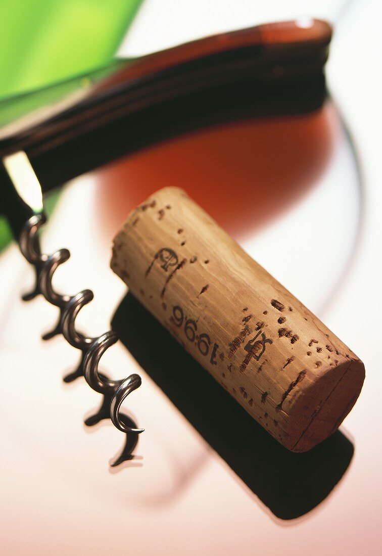 Wine cork, corkscrew and glass of red wine