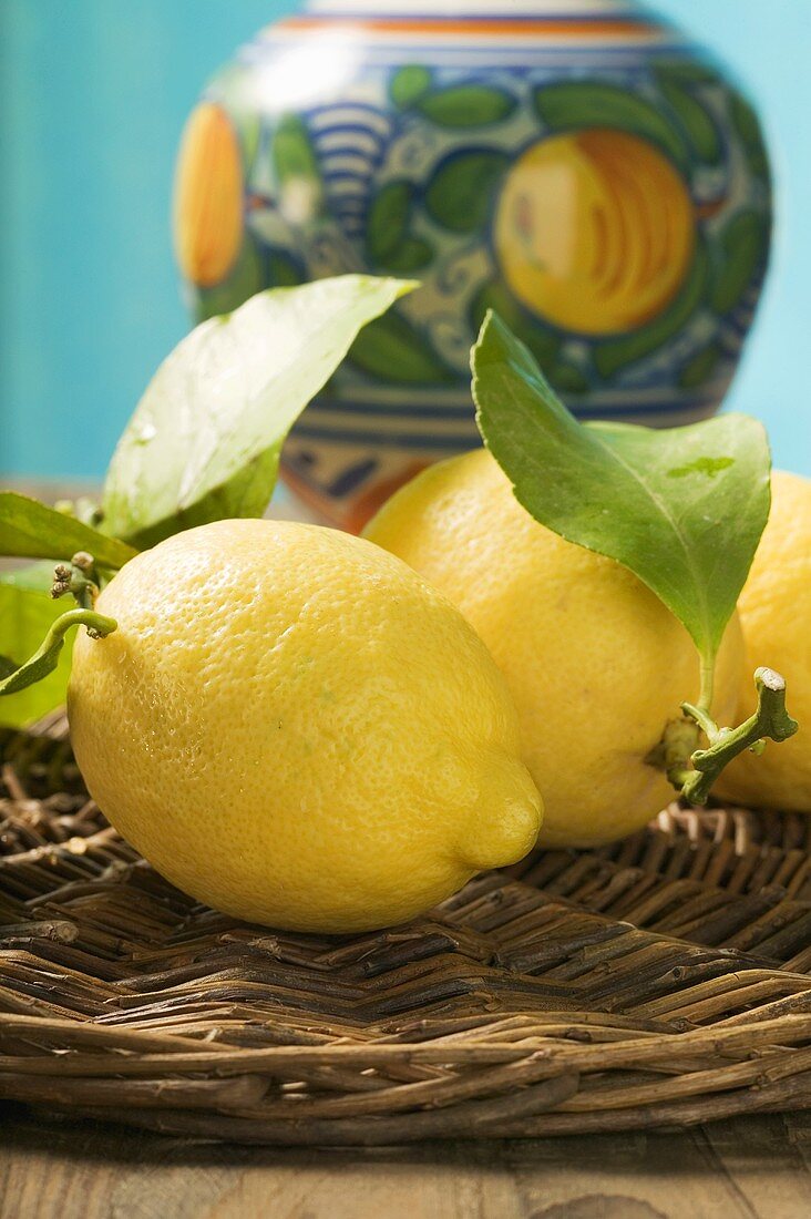 Fresh lemons with leaves on wicker tray