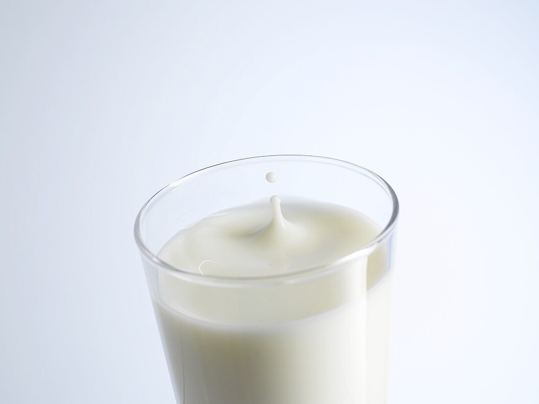 A glass of milk with a drop of milk