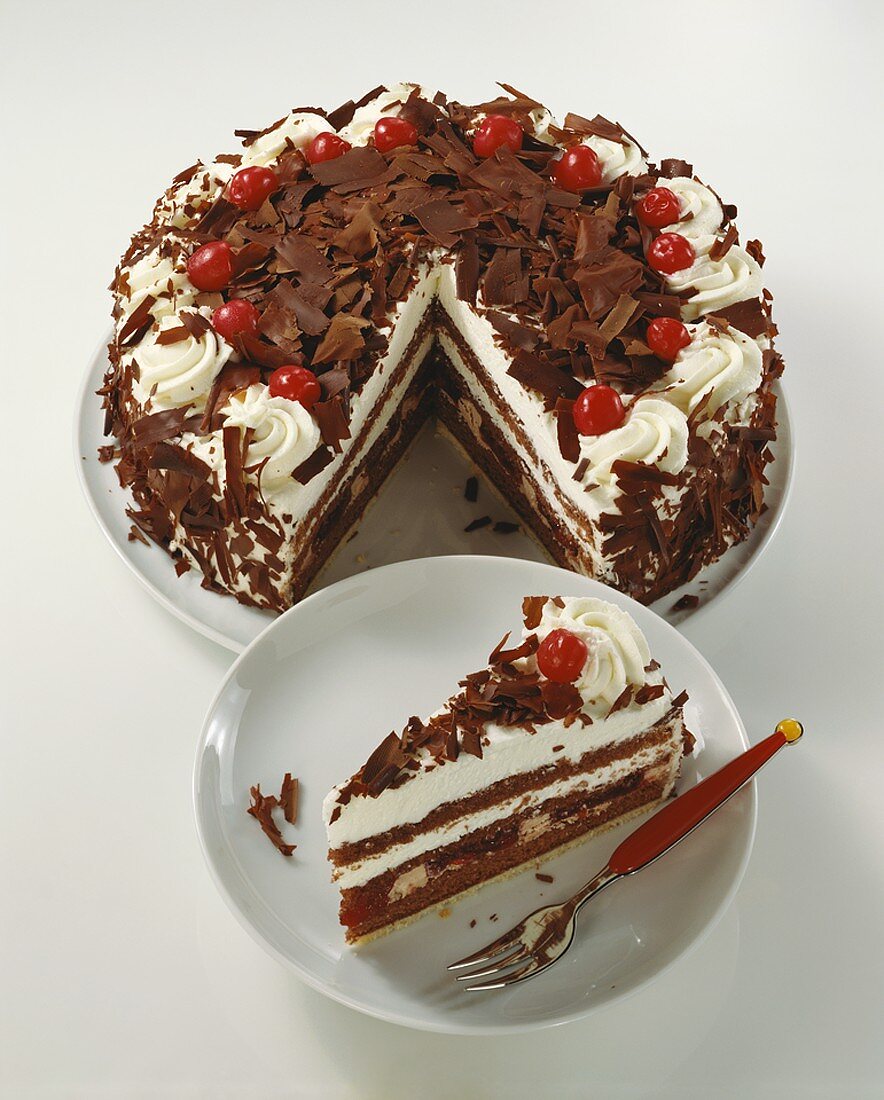 Black Forest gateau with pieces taken & a piece on a plate