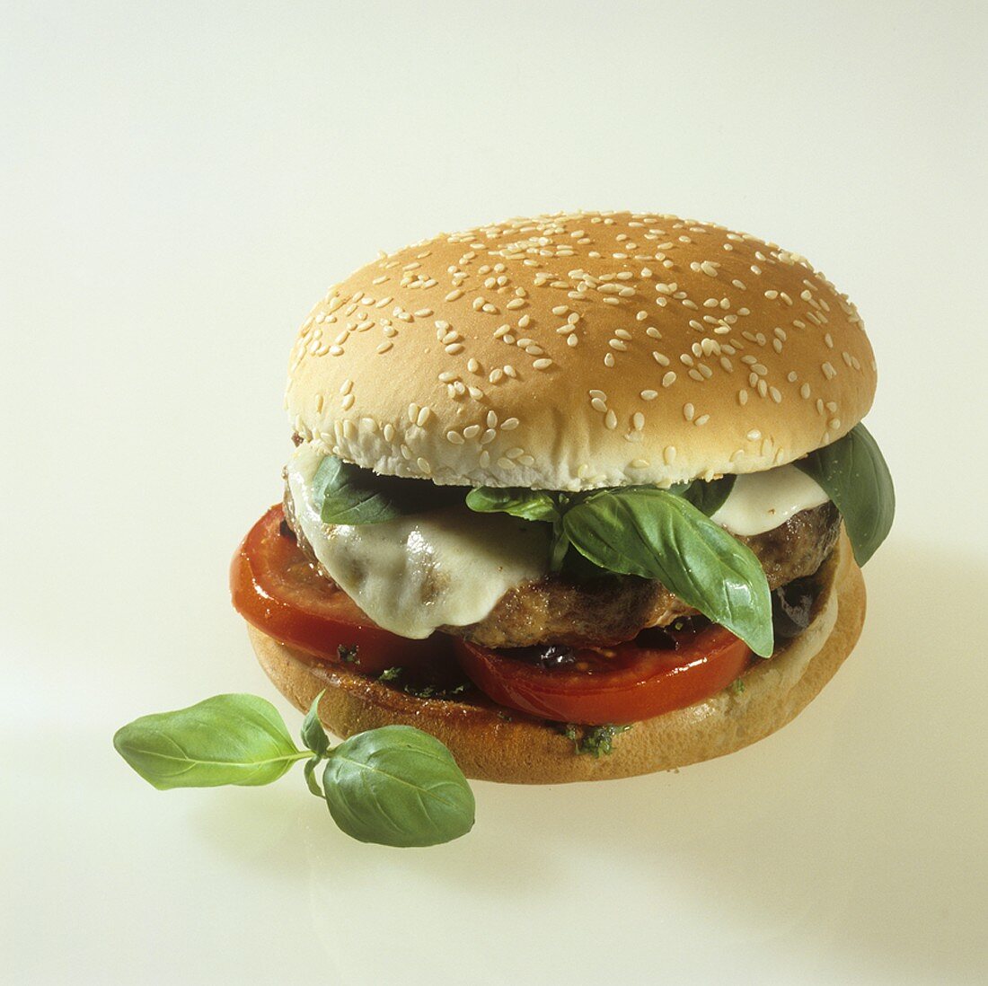 A hamburger with basil leaves