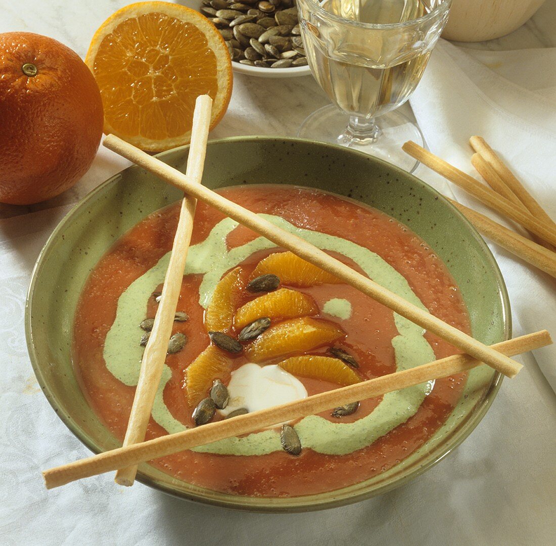 Creamed tomato soup with orange segments, pumpkin seeds & grissini