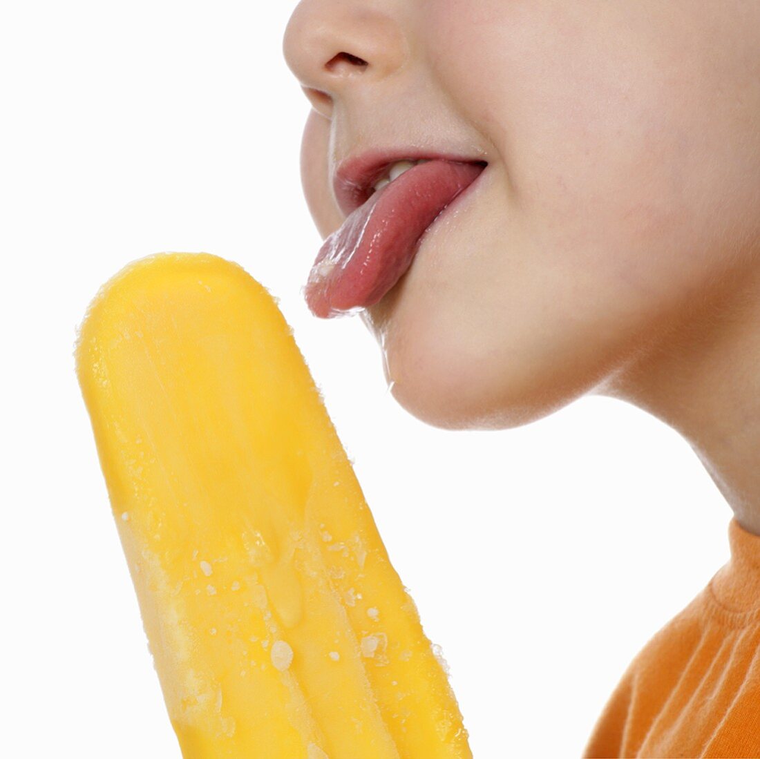 Boy licking an orange ice lolly