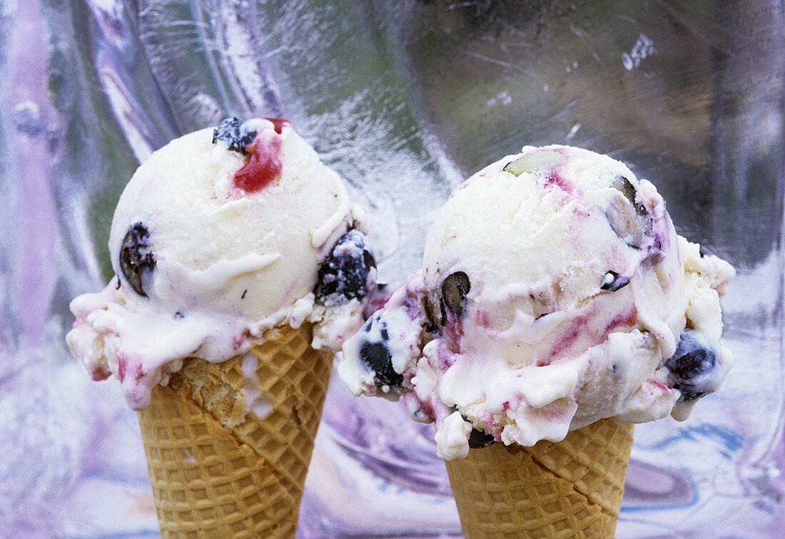 Two blueberry and cherry ice creams in waffle cones