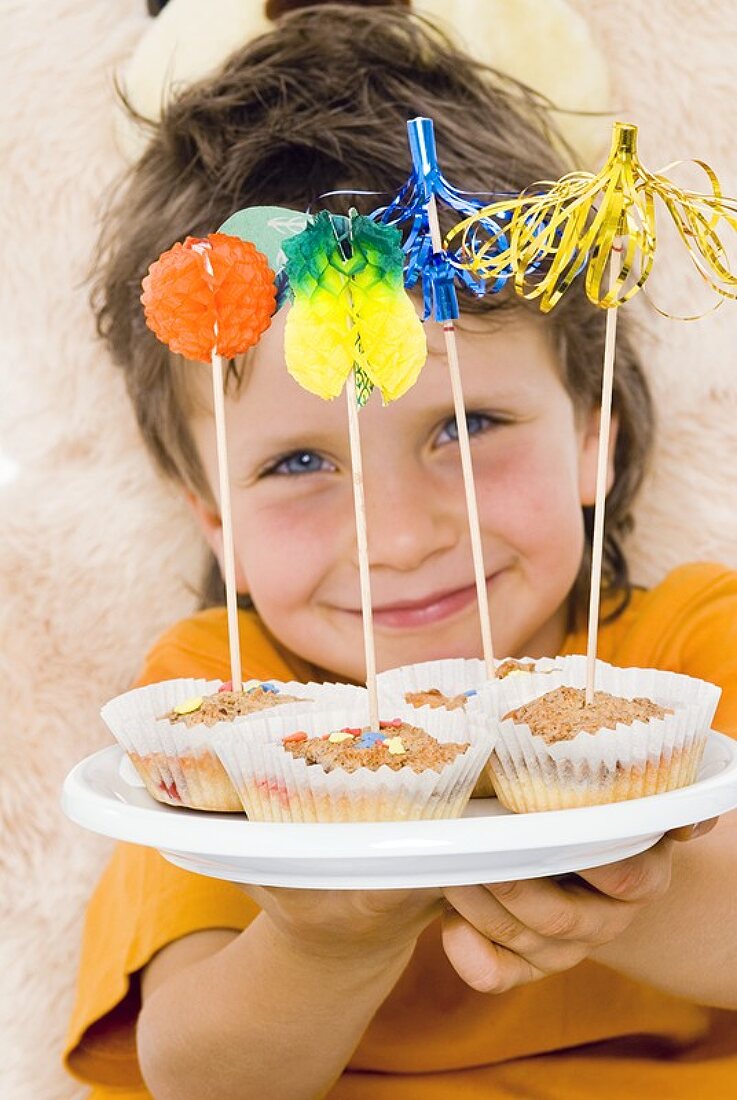 Junge präsentiert ein Tablett mit Muffins