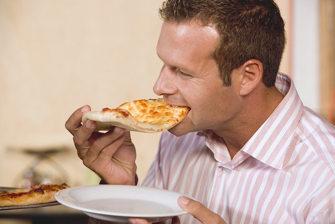 Man biting into a piece of pizza