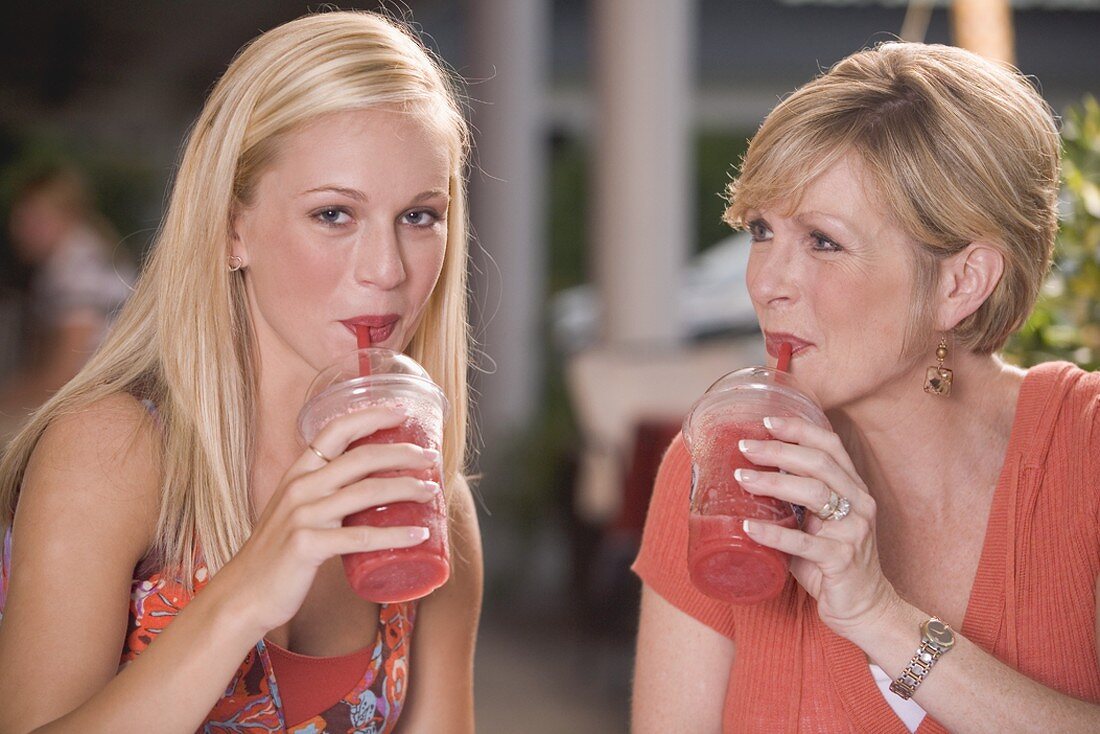 Young woman & mature woman drinking frozen strawberry smoothies
