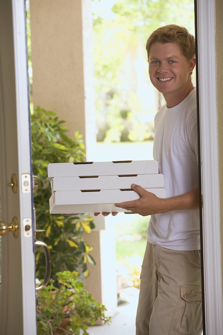 Man standing at house door with pizza boxes