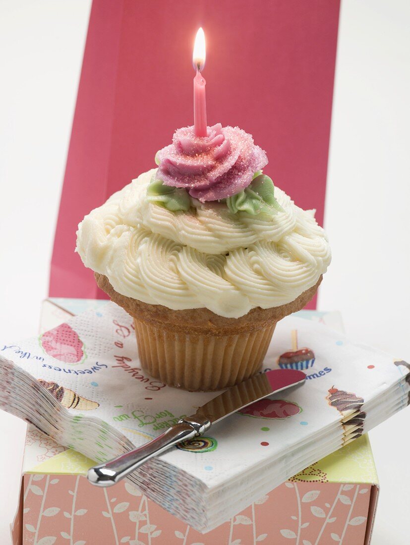 Ein Cupcake mit einer Geburtstagskerze auf Serviettenstapel
