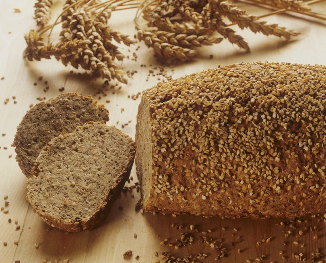 Wholemeal wheat bread with sesame crust, ears of wheat behind