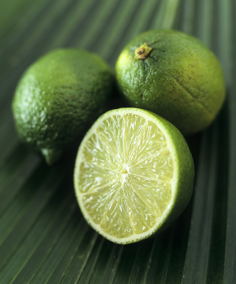 Limes, two whole and one half, on a palm leaf