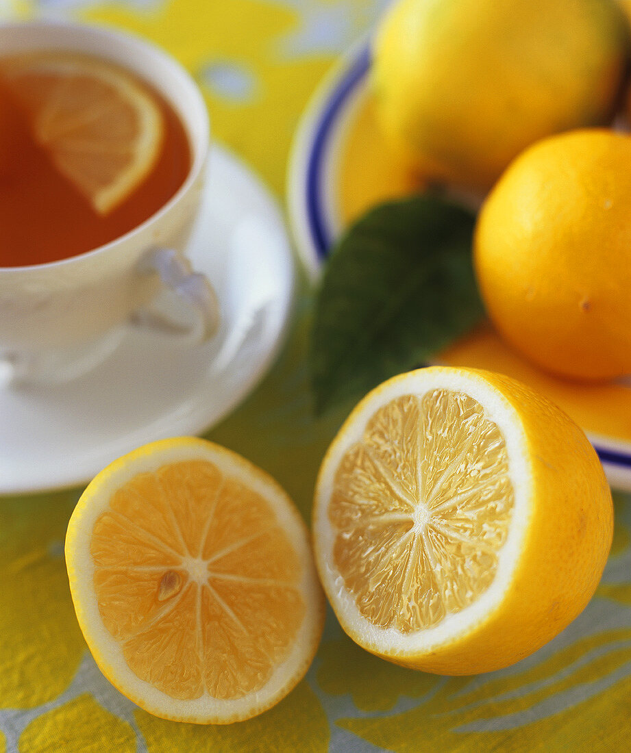 Cup of tea with whole and halved lemons