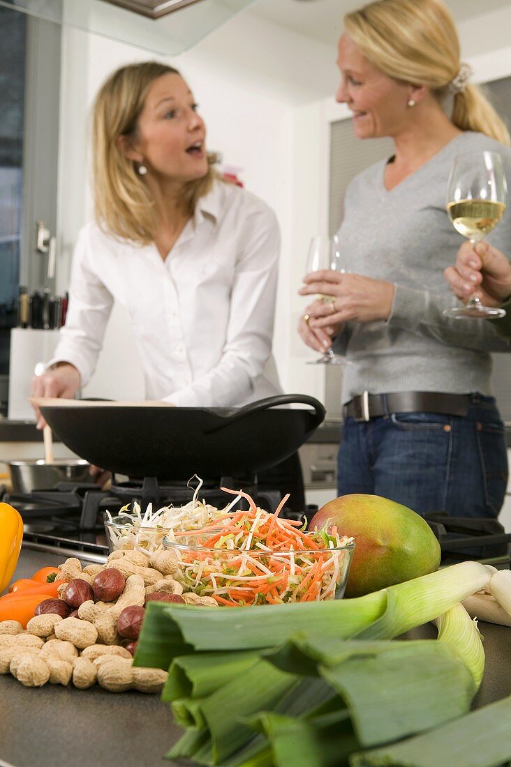 Frauen mit Weingläsern unterhalten sich beim Kochen