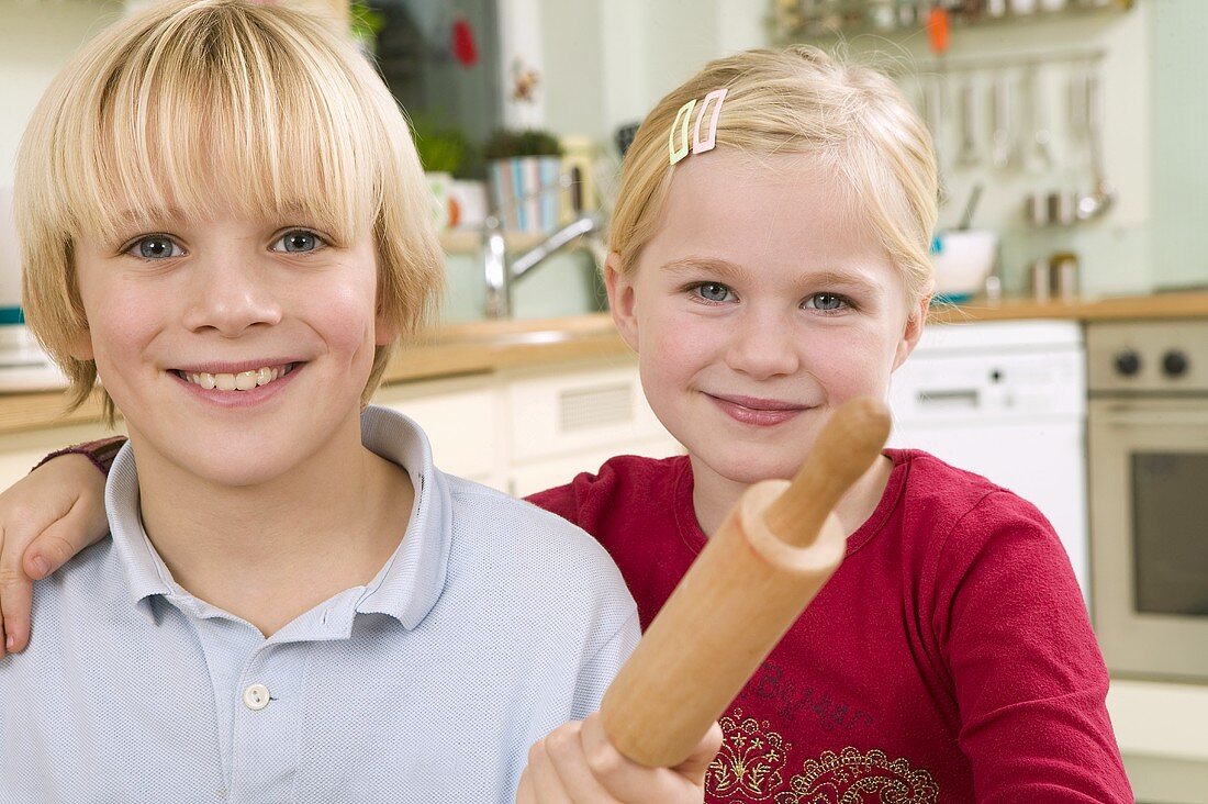Girl and boy with rolling pin in a kitchen