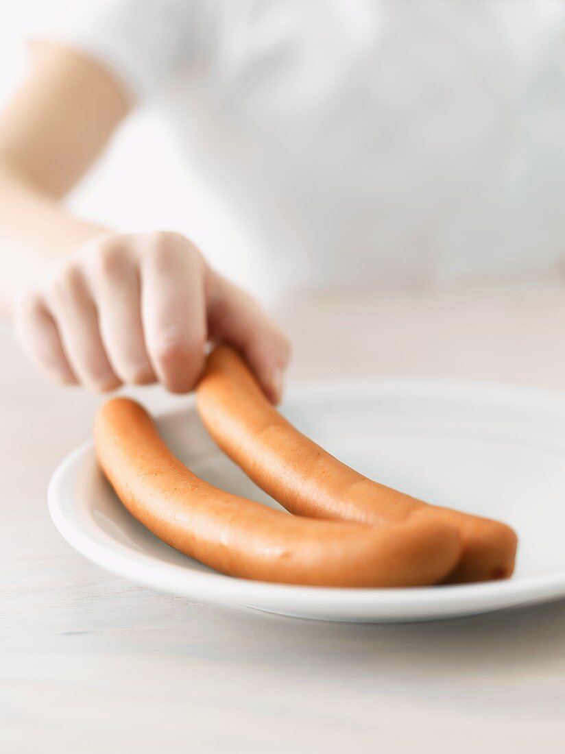 Child's hand reaching for a frankfurter