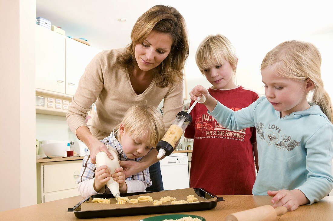 Mother and children making piped biscuits
